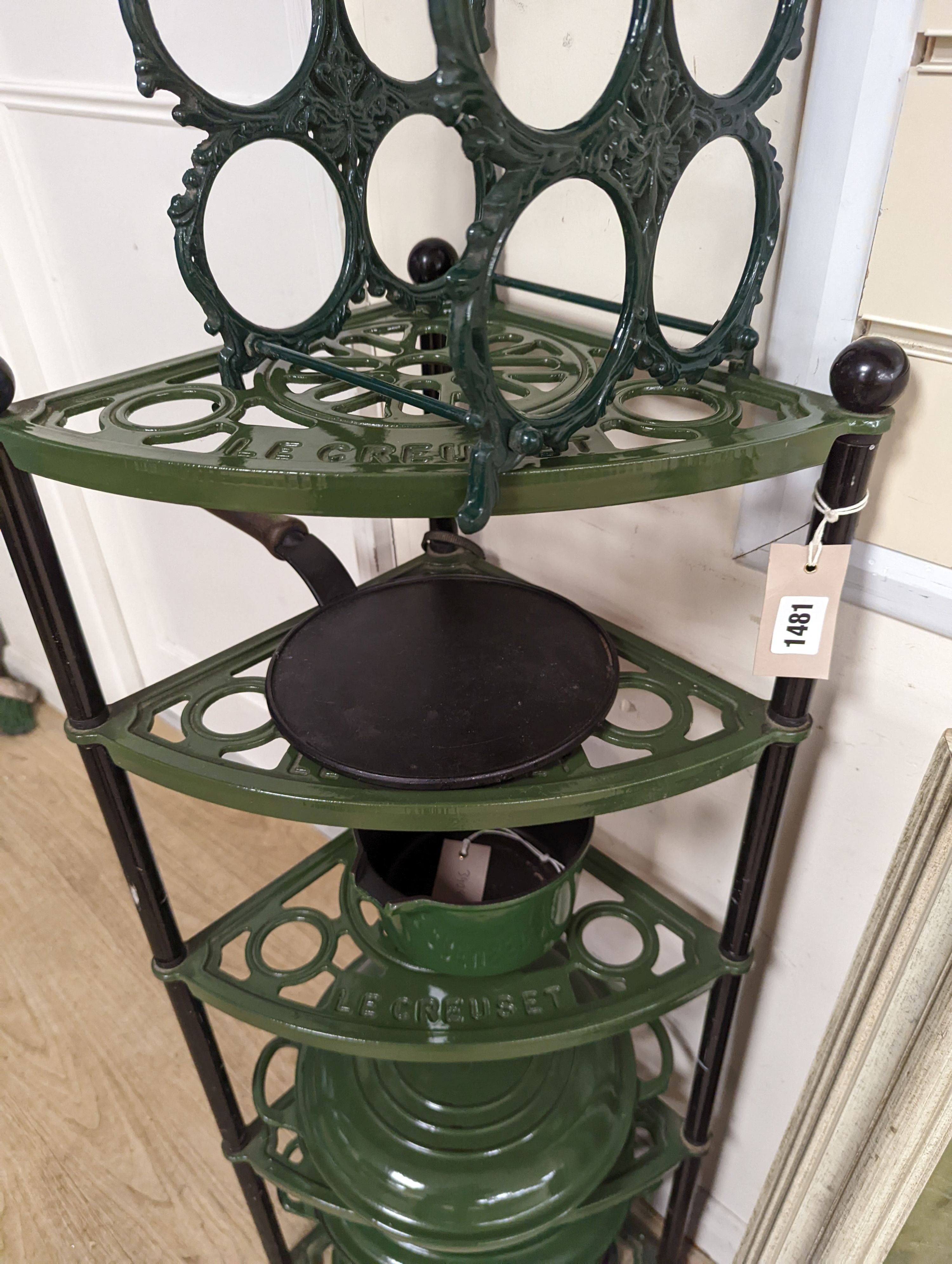 A green enamel Le Cruset pot stand, three pans and a bottle rack, stand 90 cms high.